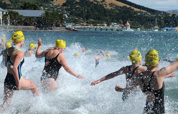 swimmers running into the ocean at a competitive swim event