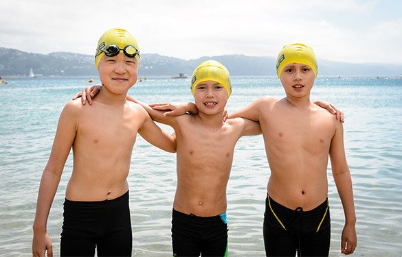 three children in swimsuits at an ocean swim event